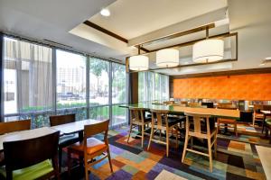 Fairfield Inn & Suites Dallas Medical/Market Center في دالاس: غرفة طعام بها طاولات وكراسي ونوافذ كبيرة