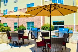 a patio with tables and chairs with umbrellas at TownePlace Suites Stafford in Stafford