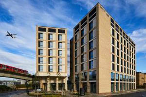 a plane flying over a tall building with a train at Courtyard by Marriott London City Airport in London