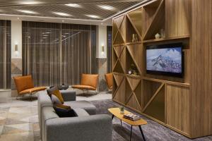 a living room with couches and a tv on a wall at Courtyard by Marriott London City Airport in London