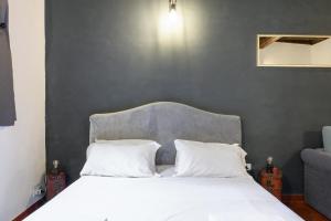 een bed met een grijs hoofdeinde en witte kussens bij Monserrato Apartment in Rome