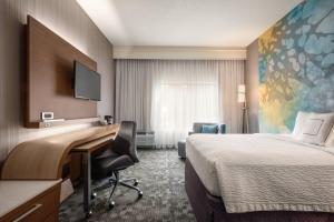 a hotel room with a desk and a bed at Courtyard by Marriott Dayton North in Dayton