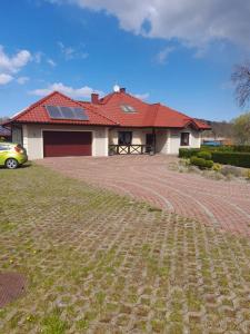 una casa con tetto rosso e vialetto di mattoni di Apartamenty Pod Debem (Ferienwohnungen an der uralten Eiche) a Wapnica