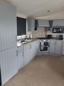 a kitchen with white cabinets and a sink at Haven Dreams Caravan in Hastings +8 photos