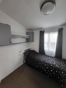 a small bedroom with a black bed and a window at Haven Dreams Caravan in Hastings