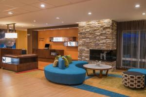 a lobby with a fireplace and a blue chair and a table at Fairfield Inn & Suites by Marriott Fort Wayne Southwest in Ellison