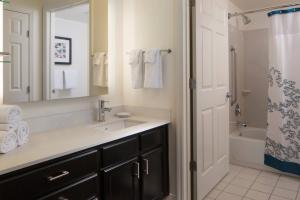 a bathroom with a sink and a mirror and a tub at Residence Inn by Marriott Orlando at SeaWorld in Orlando