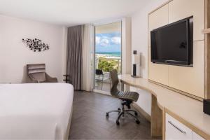 a hotel room with a bed and a desk and a television at Marriott Stanton South Beach in Miami Beach