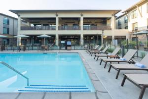 une piscine avec des chaises longues et un bâtiment dans l'établissement Courtyard by Marriott Thousand Oaks Agoura Hills, à Agoura Hills