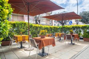 um pátio com mesas e cadeiras com guarda-sóis em Hotel Paolina em Viareggio