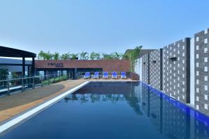 a swimming pool with chairs on the side of a building at Courtyard by Marriott Nashik in Nashik