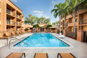 una piscina con sillas y un complejo en Courtyard Fort Myers Cape Coral, en Fort Myers