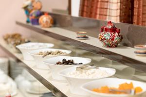 Un estante con cuencos blancos y un jarrón encima. en Makon Hotel, en Ferganá 15 fotos más