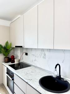 uma cozinha com um lavatório preto e armários brancos em Aqua Vista Infinity Spa & Pool Studio Lux em Mamaia Nord – Năvodari