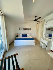 Beach Paradise Nilaveli في ترينكومالي: غرفة نوم بيضاء مع سرير وسقف