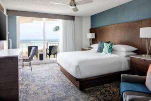 a hotel room with a bed and a balcony at Marriott Hutchinson Island Beach Resort, Golf & Marina in Stuart