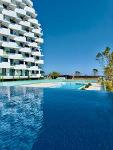 a swimming pool in front of a large building at Aqua Vista Infinity Resort & Spa - Studio Lux - Piscină Infinity, Jacuzzi, Sauna, Gym - Privat in Mamaia Sat/Năvodari