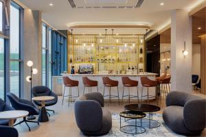 a bar in a hotel lobby with chairs and tables at Courtyard by Marriott Paris Charles de Gaulle Central Airport in Roissy-en-France
