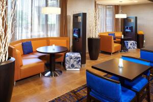 una sala de espera con mesas, sillas y TV en Courtyard Kansas City Overland Park / Convention Center, en Overland Park