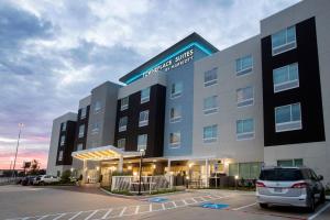 a building with a car parked in a parking lot at TownePlace Suites by Marriott Conroe in Conroe