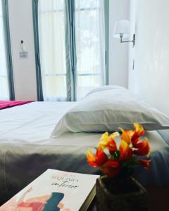 a vase of flowers on a table next to a bed at Hotel Alcazar in Buenos Aires