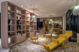 ein Geschäft mit gelben Stühlen und Tischen in einem Zimmer in der Unterkunft The Jangle Hotel - Paris - Charles de Gaulle - Airport in Le Mesnil-Amelot