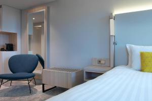 um quarto com uma cama, uma cadeira e uma secretária em The Jangle Hotel - Paris - Charles de Gaulle - Airport em Le Mesnil-Amelot