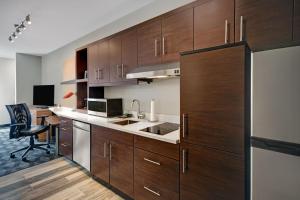 TownePlace Suites by Marriott Grand Rapids Wyoming في وايومنغ: مطبخ مع دواليب خشبية ومكتب في الغرفة