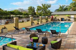 uma piscina num hotel com cadeiras e uma mesa em Fairfield Inn & Suites Fort Lauderdale Airport & Cruise Port em Dania Beach