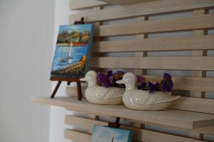 drei weiße Enten auf einem Holzregal in der Unterkunft Apartman Ariana in Selce