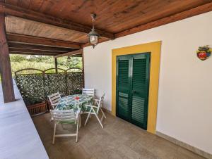 einen Tisch und Stühle auf einer Terrasse mit grüner Tür in der Unterkunft Ponza Holiday Homes - Santa Maria in Ponza