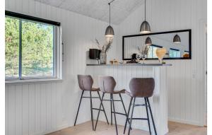 a kitchen with three bar stools and a counter at Gorgeous Home In Nørre Nebel With Sauna in Nørre Nebel +30 photos