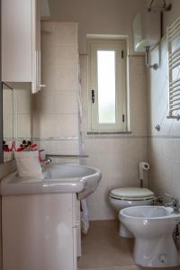 uma casa de banho branca com um lavatório e um WC em Villa Emma em Castellabate