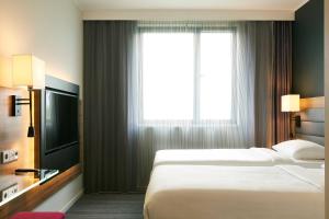 a hotel room with two beds and a window at Moxy Paris Charles de Gaulle Airport in Roissy-en-France