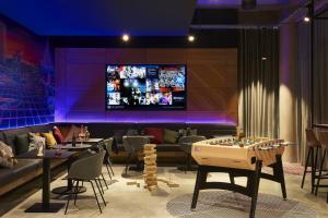 a restaurant with tables and a tv on the wall at Moxy Paris Charles de Gaulle Airport in Roissy-en-France