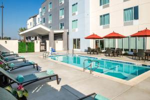 una piscina in un hotel con sedie e ombrelloni di TownePlace Suites by Marriott Ontario Chino Hills a Chino Hills