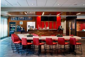 a restaurant with a large table and red chairs at Courtyard by Marriott Minneapolis West in Saint Louis Park