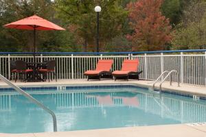 einen Pool mit Stühlen, einem Tisch und einem Sonnenschirm in der Unterkunft Fairfield Inn Greenville Spartanburg Airport in Greenville