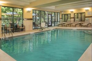 a pool in a hotel with chairs and tables at Courtyard by Marriott Hershey Chocolate Avenue in Hershey