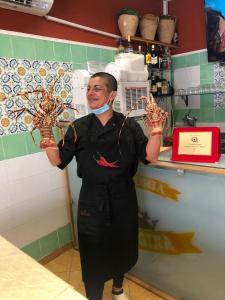 リド・マリーニにあるCasavacanza La Reginaのキッチンに立って物を持っている女性
