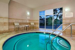 Fairfield Inn & Suites by Marriott Fairfield Napa Valley Area في فيرفيلد: حمام سباحة ساخن في غرفة الفندق مع طاولة وكراسي