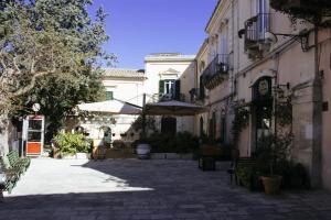un patio con bancos y sombrillas en un edificio en Risveglio Ibleo, en Ragusa