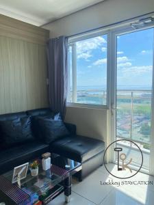 a living room with a couch and a large window at 180 degree view of manila bay in Manila