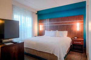 a hotel room with a bed and a flat screen tv at Residence Inn by Marriott Raleigh Crabtree Valley in Raleigh