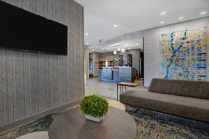 - un salon avec un canapé et une télévision murale dans l'établissement TownePlace Suites by Marriott Phoenix Glendale Sports & Entertainment District, à Glendale