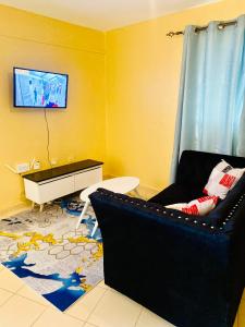 - un salon avec un canapé et une télévision murale dans l'établissement Warm & Spacious 1br in Lower Kabete near KSG, à Nairobi