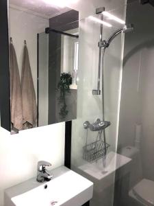 een witte badkamer met een wastafel en een douche bij Moderne og sentral leilighet med koselig og privat uteplass! in Hornnes