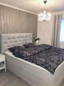 een slaapkamer met een groot bed en een kroonluchter bij Moderne og sentral leilighet med koselig og privat uteplass! in Hornnes