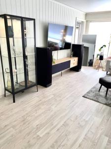 a living room with glass cases and a wooden floor at Moderne og sentral leilighet med koselig og privat uteplass! in Hornnes