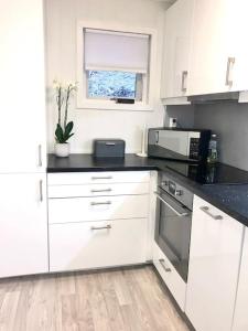 a kitchen with white cabinets and a black counter top at Moderne og sentral leilighet med koselig og privat uteplass! in Hornnes